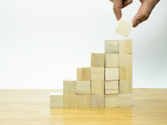 A person placing a piece of wood into a pyramid