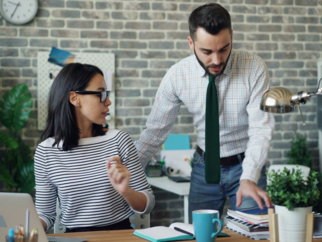 a man and a woman standing in front of a laptop