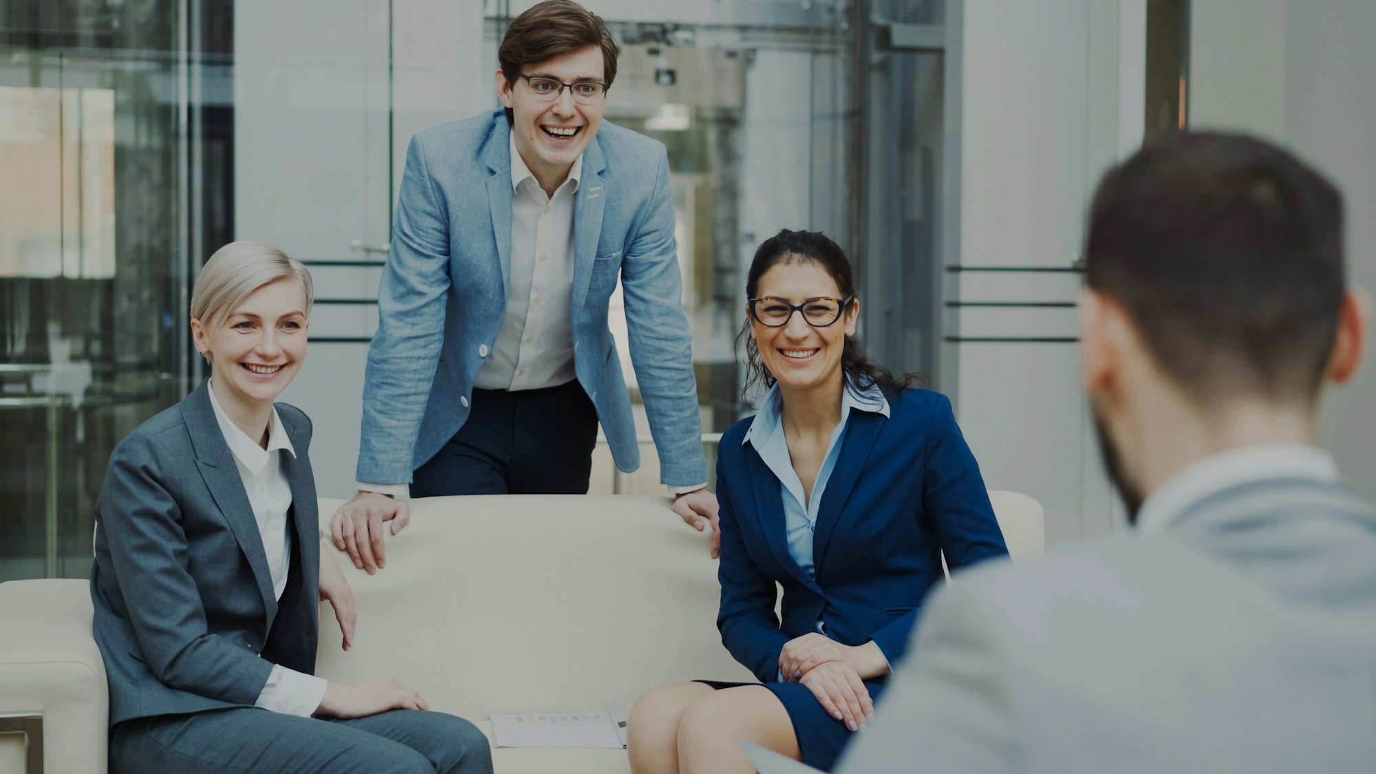 Four smiling business people in a modern office.